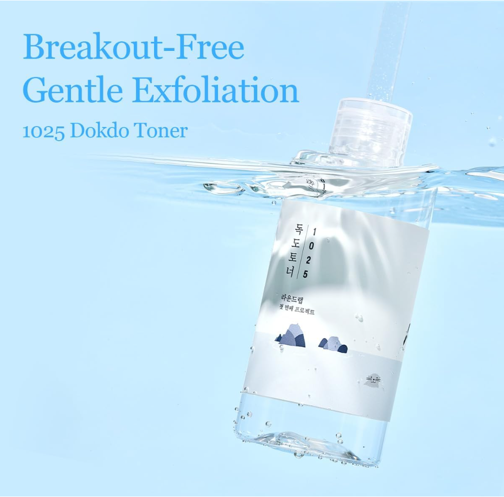 Bottle of 1025 Dokdo Toner with water splashing around it on a light blue background, Round Lab 1025 Dokdo Toner 500ml
