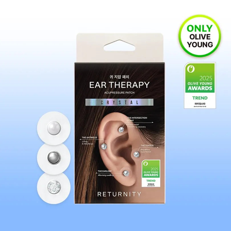 Packaged ear therapy acupressure patch set by RETURNITY, featuring three white circular patches with silver and clear crystal elements on the left, and the product box in the center. The box displays an illustration of an ear with crystals inserted and award badges on the right.